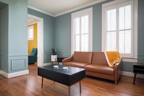 A living room with a brown leather sofa, a black coffee table, and a yellow throw blanket.
