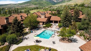 Zona residencial con piscina rodeada de casas, un patio y montañas al fondo.