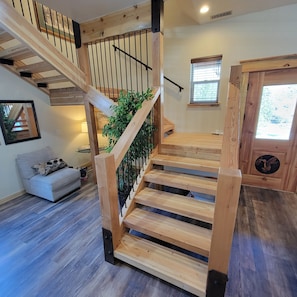 A wooden staircase with a railing, a small plant, and a door with a circular window.