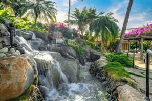 A waterfall feature with a sign warning against touching the rocks. - Maui Kamaole by Maui Rental Group (Kihei)