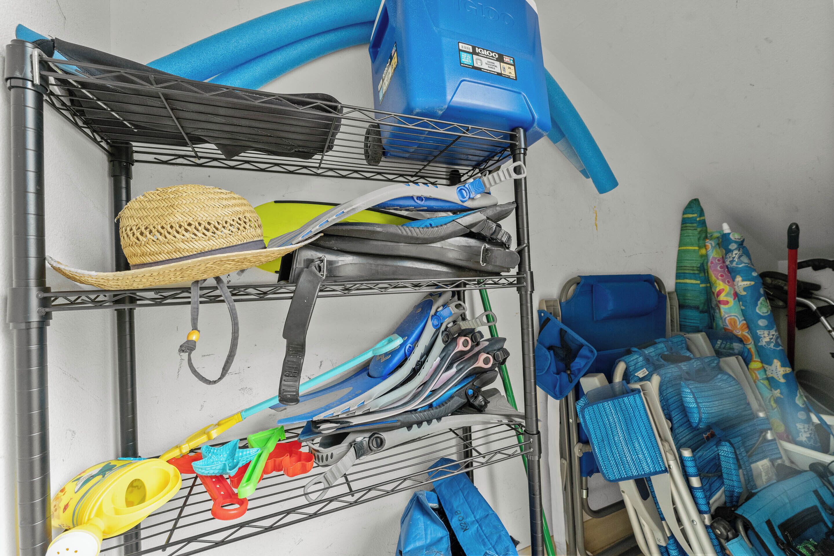 A metal rack with various items including a straw hat, a blue water container, and a pair of skis.
