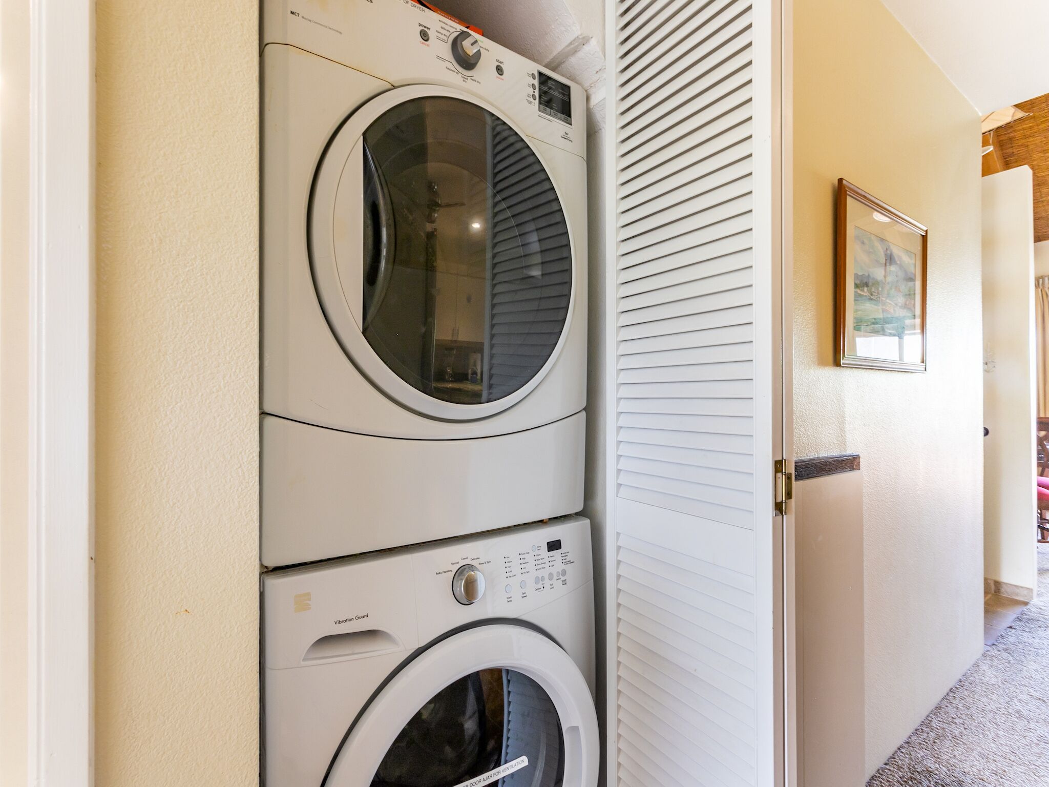 A stacked washer and dryer unit in a hallway.