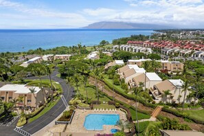 A resort with a swimming pool, palm trees, and a view of the ocean. - Maui Kamaole by Maui Rental Group (Kihei)