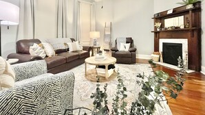 A living room with a sofa, armchairs, a coffee table, a fireplace, and a ceiling fan. - Cozy Getaway | Splendid Historic Thibodaux Gem (Thibodaux)