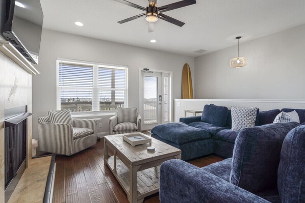 A living room with a sofa, chairs, a coffee table, a TV, and a ceiling fan.
