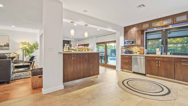 A modern kitchen with wooden cabinets, a built-in microwave, and a large window. - Family Beach Villa w/ Home Theater & Heated Pool! (Hollywood)