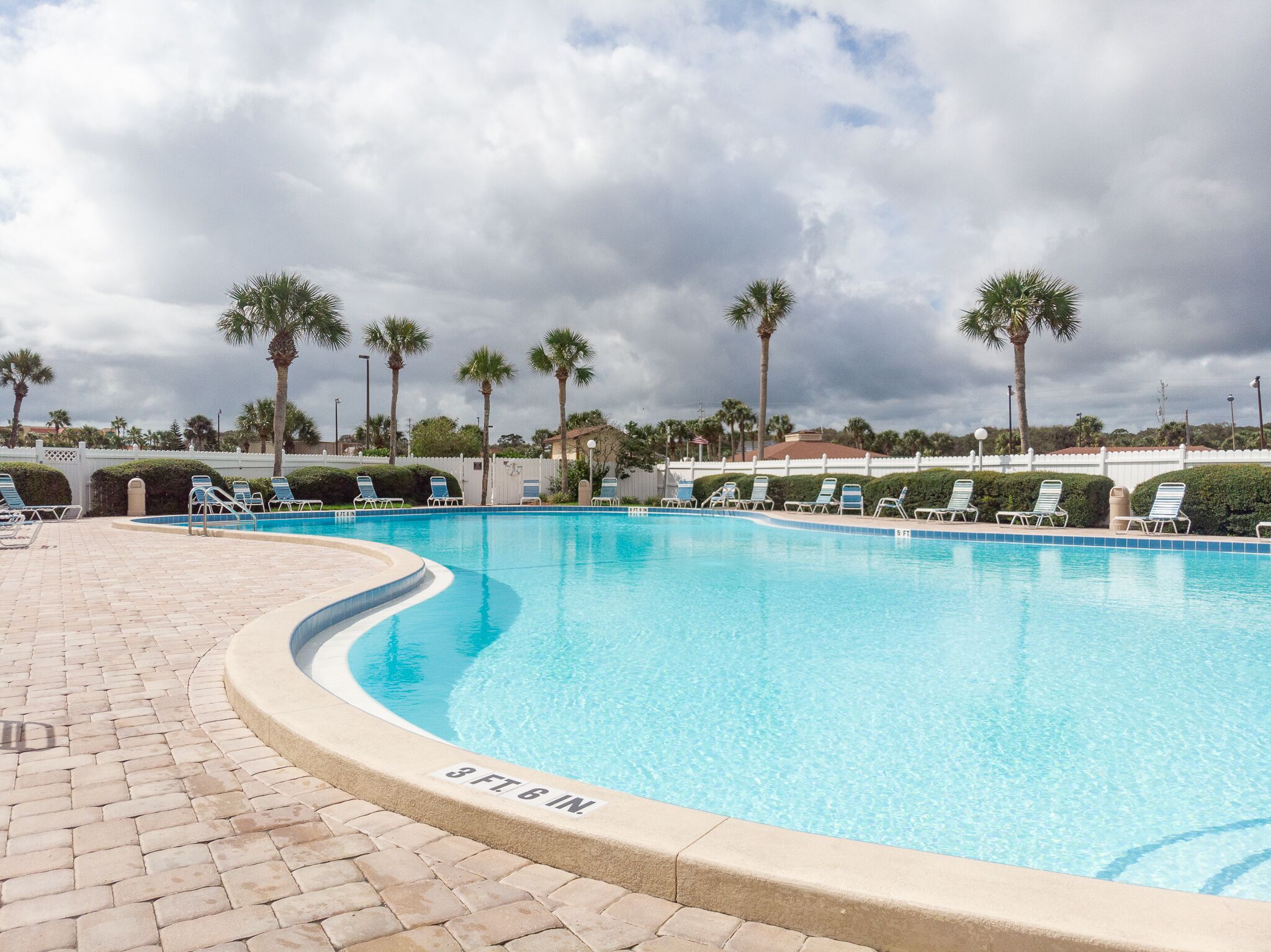 A swimming pool with lounge chairs and palm trees.