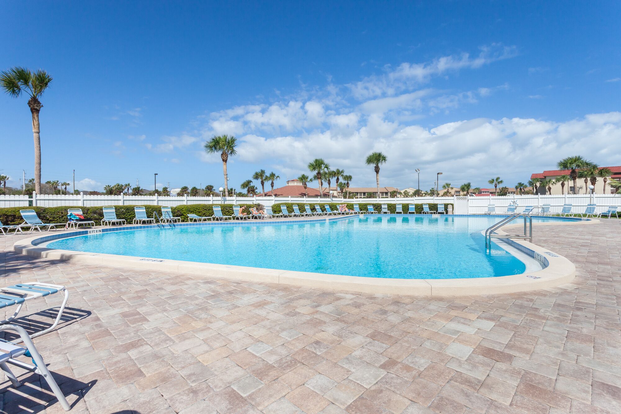 A swimming pool with lounge chairs and palm trees.