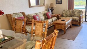 A living room with a glass dining table, two sofas with tropical prints, and ceiling fans. - Discover Your Island Oasis: St. Thomas Condo (St. Thomas)