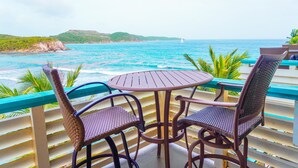 A round table with two wicker chairs, overlooking a turquoise sea with a sailboat in the distance. - Discover Your Island Oasis: St. Thomas Condo (St. Thomas)