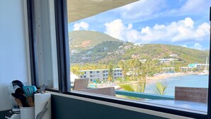 A kitchen counter with a window overlooking a beach and resort area. - Stunning St. Thomas Condo for Your Tropical Escape (St. Thomas)