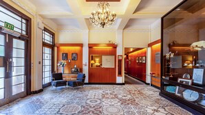 A hotel lobby with patterned flooring, a reception desk, seating area, and a chandelier. - Wigram Hotel (Christchurch)