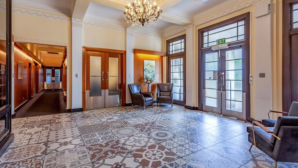 A spacious lobby with patterned floor tiles, a chandelier, and two leather armchairs. - Wigram Hotel (Christchurch)