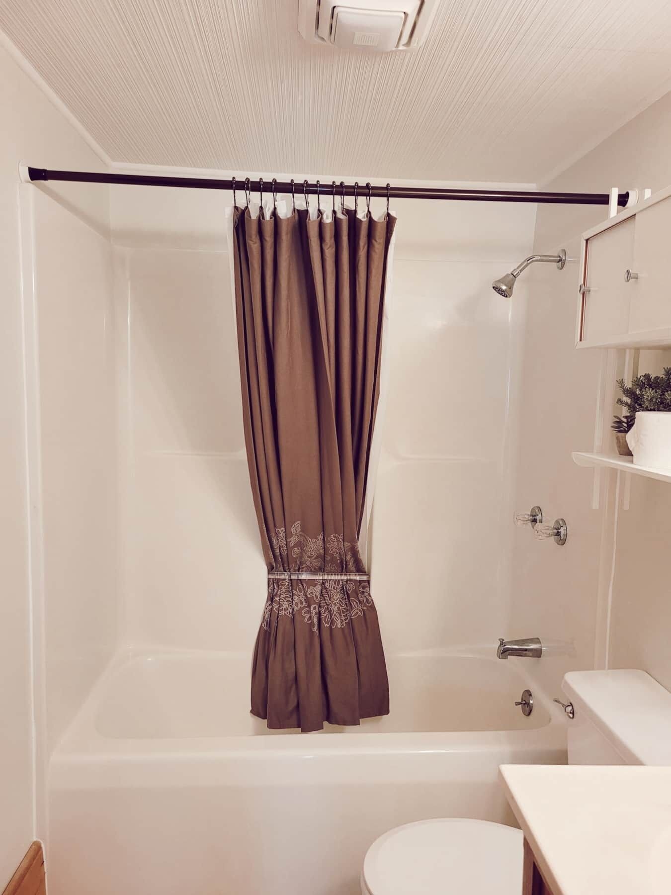 Een badkamer met een bad, douche en toilet.