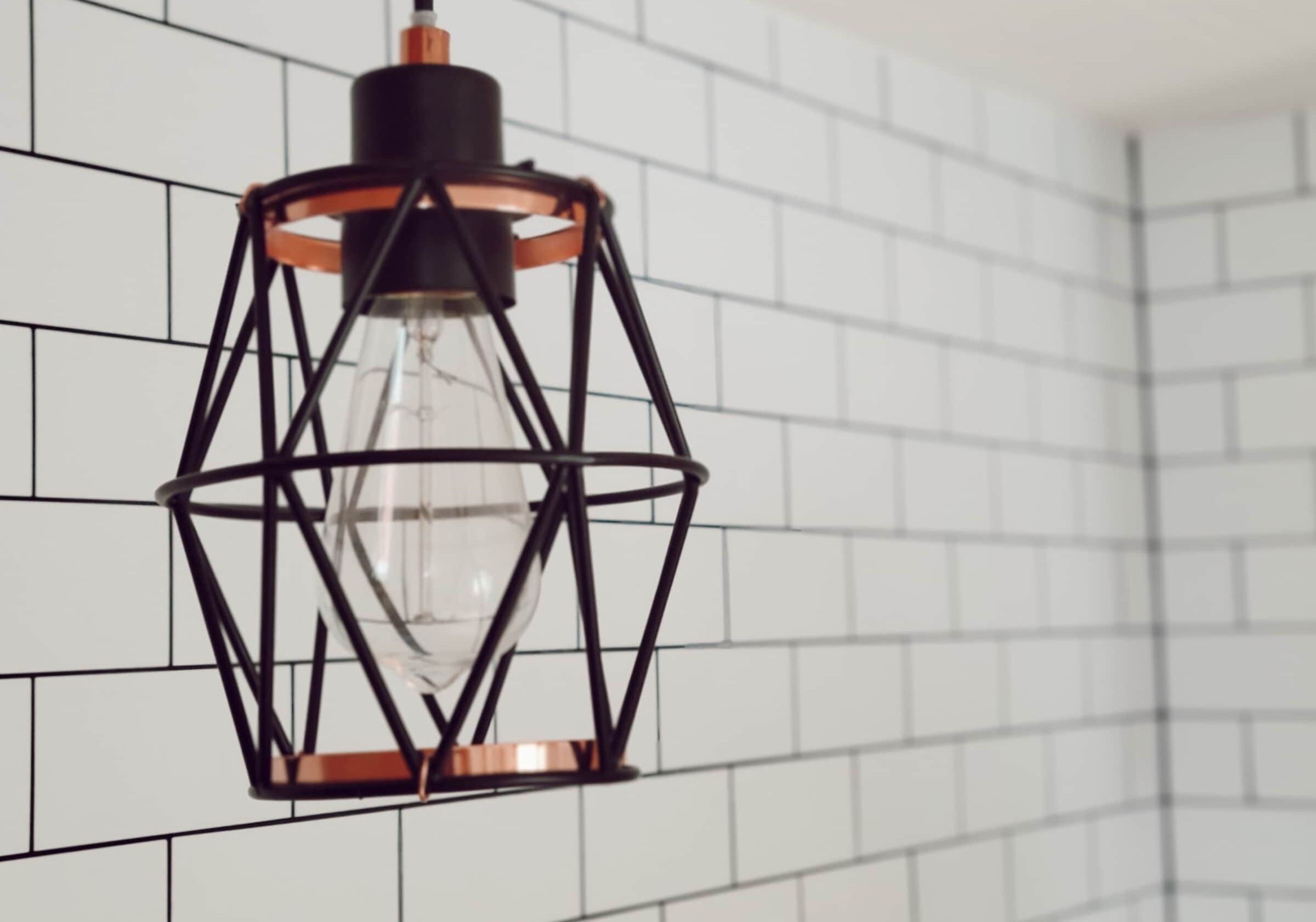A pendant light fixture with a geometric metal frame and a clear glass bulb, hanging from a ceiling.