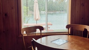 A wooden dining room with a large window, a table, and four chairs.