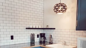 A modern kitchen with white subway tiles, blue cabinets, a wooden ceiling, and a geometric pendant light. - Cabin 4 | Moonbeam (Nevis Township)