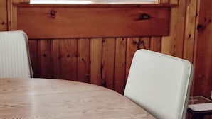 Une pièce aux murs lambrissés, avec une table ronde et des chaises blanches.