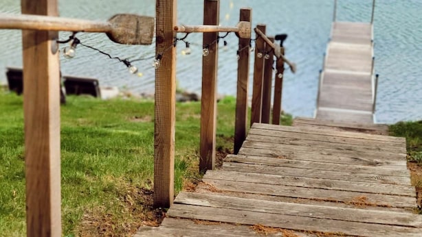 Un escalier en bois qui descend vers une jetée au bord d’un lac.