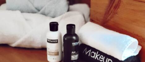 Une boîte en bois contenant une serviette enroulée étiquetée « Maquillage » et deux flacons de produits de soins pour la peau, le tout posé sur une surface en bois.