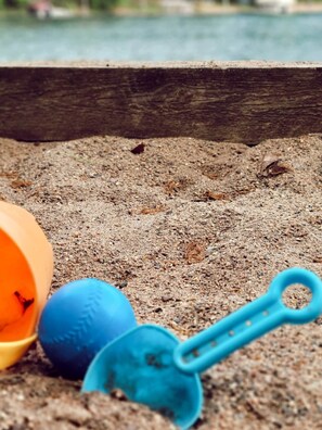 A sandy area with a blue shovel and a blue ball. - Cabin 6 | Voyageur (Nevis Township)