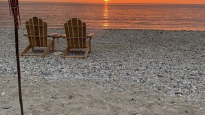 A beach with two Adirondack chairs and a tiki torch. - Modern Farmhouse Steps to Beach and Love Lane  (Mattituck)
