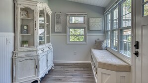 A room with a white bench, a large white cabinet, and two windows. - Modern Farmhouse Steps to Beach and Love Lane  (Mattituck)