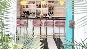 A bar area with a counter, shelves of bottles, and three bar stools. - Modern Farmhouse Steps to Beach and Love Lane  (Mattituck)