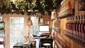 A rustic bar area with wooden barrels, a computer, and a wall of wine bottles. - Modern Farmhouse Steps to Beach and Love Lane  (Mattituck)