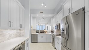 A modern kitchen with stainless steel appliances, white cabinetry, and a central island.