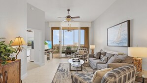 A spacious living room with a sofa, armchairs, a coffee table, and a dining area with chairs and a table.