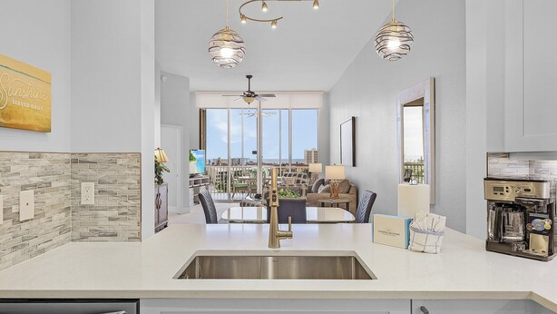 A modern kitchen with a large island, a coffee machine, and a view to the living area.