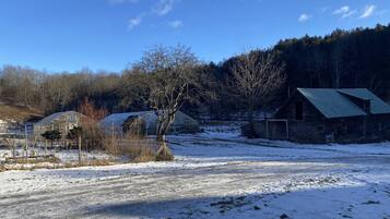 Ländliche Landschaft mit Scheune, Gewächshaus und schneebedecktem Feld.