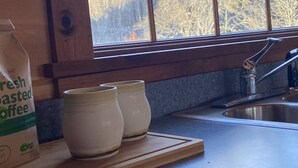 Eine Küche mit Fenster, einer Tüte frisch gerösteter Kaffe und zwei weiße Tassen auf einer Holzbrett.