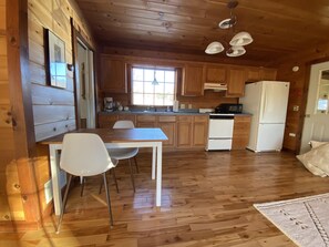 Ein Holzblockhaus im Inneren mit Küchenbereich, Esstisch und Stühlen.