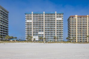 A beachfront hotel with multiple floors, balconies, and a sandy beach in the foreground. - Bluewater 1001- Family Fun In The Sun!!! (Orange Beach)