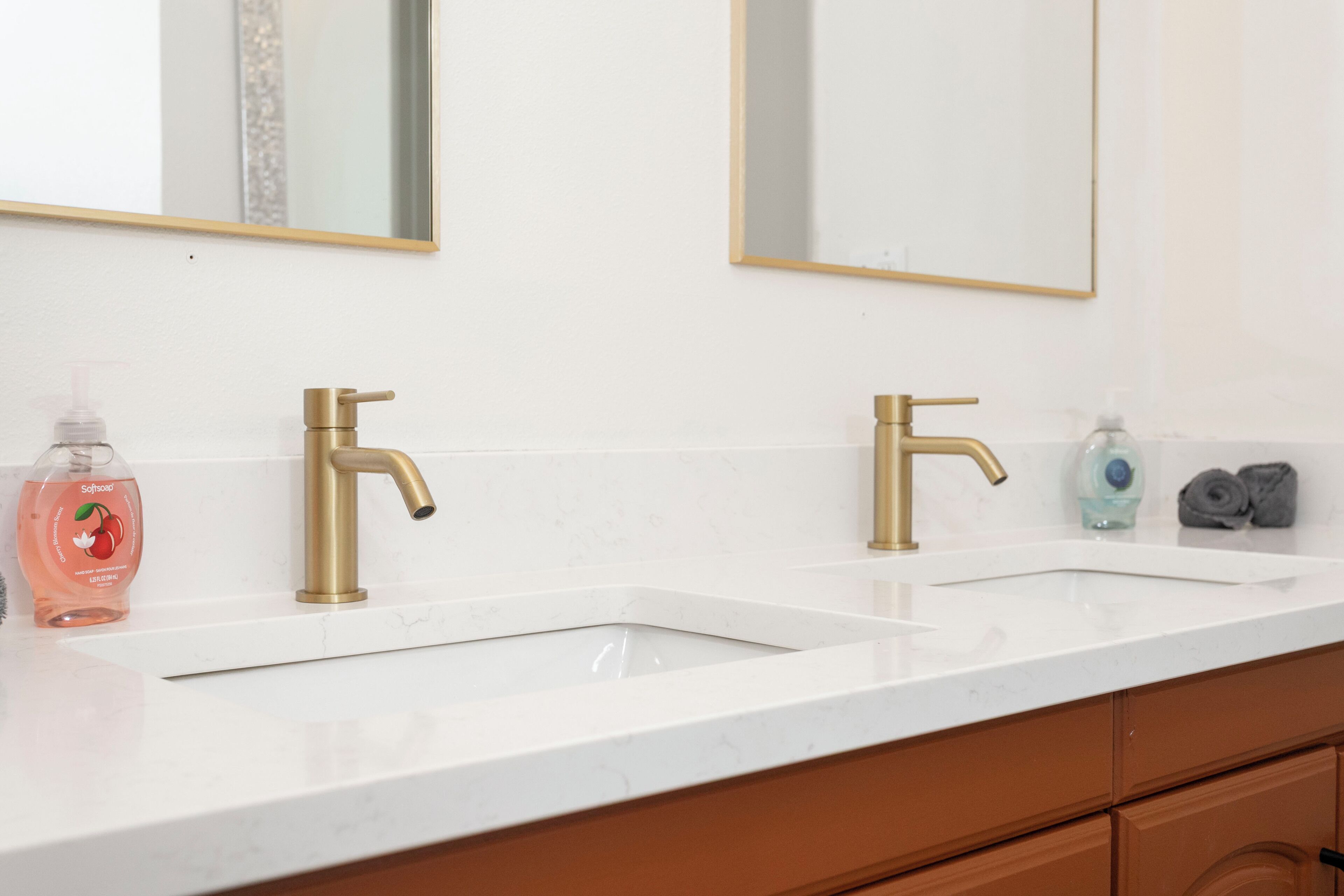A bathroom with two sinks, gold faucets, and a white countertop.