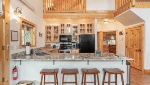 A spacious kitchen with a large island, wooden cabinets, and a high ceiling with exposed beams. - Red Feather Woodland Retreat, Family and Pet Friendly, 4 beds (Red Feather Lakes)