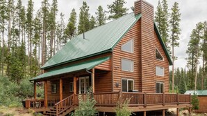 A log cabin with a green roof, a porch with wooden railings, and a chimney. - Red Feather Woodland Retreat, Family and Pet Friendly, 4 beds (Red Feather Lakes)