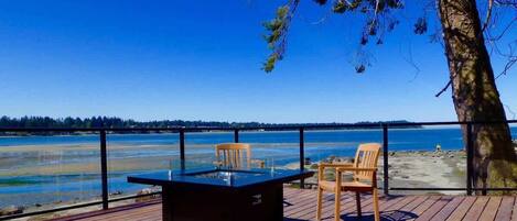 A deck with a table and chairs overlooking a body of water.