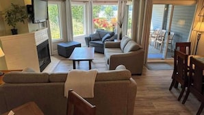Uma sala de estar com lareira, um sofá, uma mesa de centro e uma televisão.