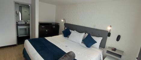 A hotel room with a bed, a nightstand, a desk, and a wardrobe.