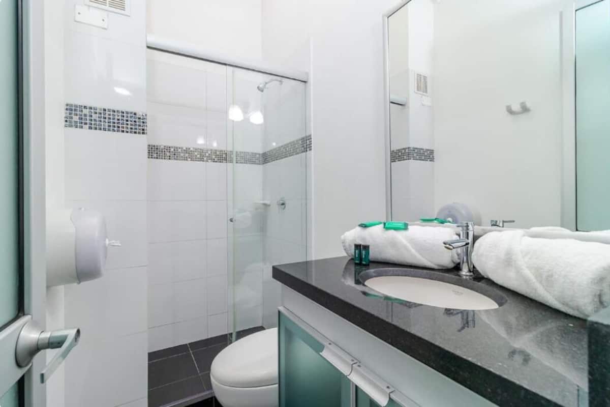 Une salle de bain moderne avec une douche à parois de verre, un lavabo avec un miroir et des toilettes.