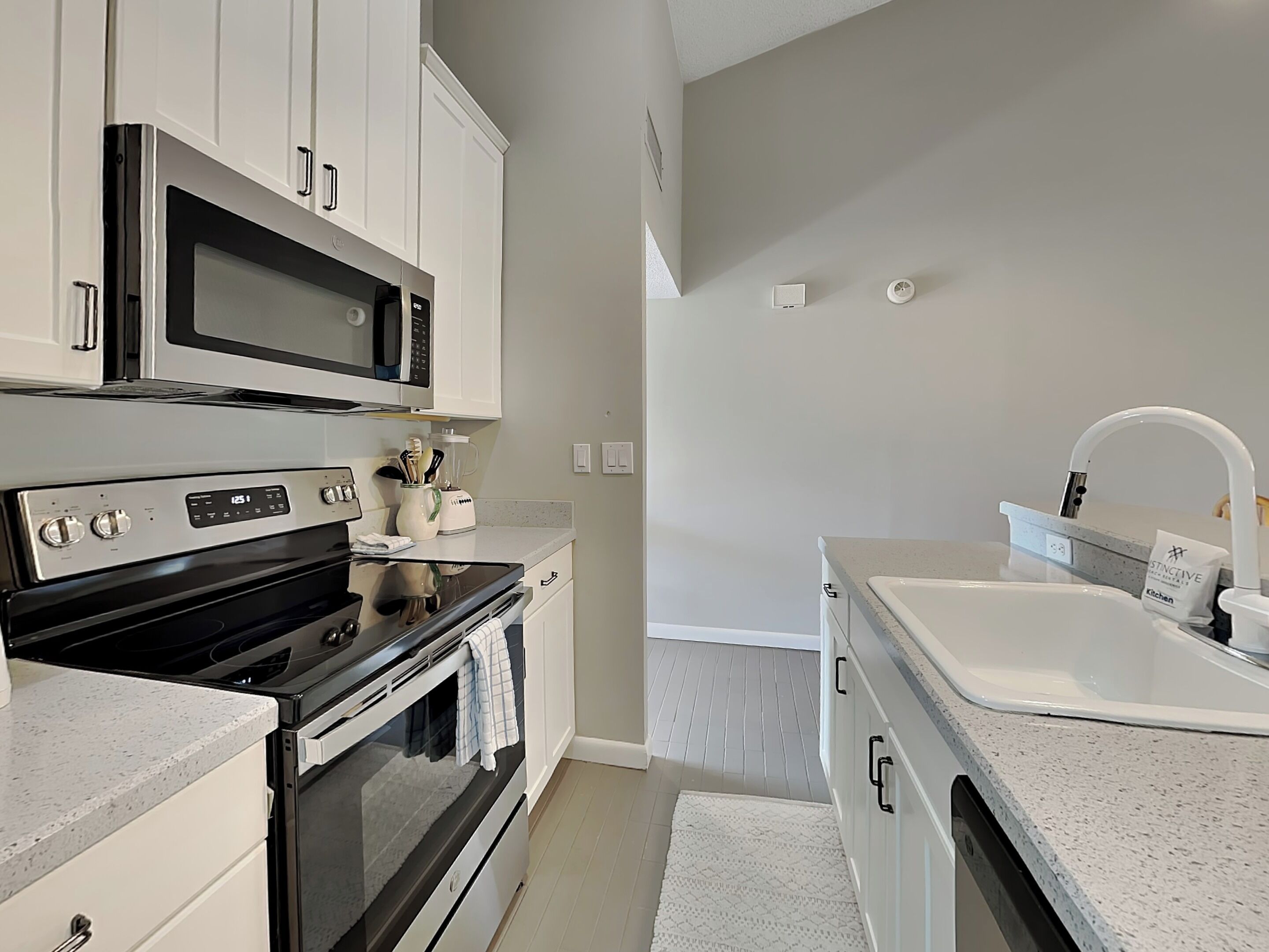 A modern kitchen with stainless steel appliances, white cabinetry, and a built-in microwave.