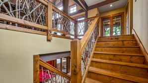 A wooden staircase with a rustic design, leading to an upper level with a view of the outdoors. - Renowned Architect! VIEWS/Theatre/Game/HotTub/FirePit/Harry Potter (Gatlinburg)