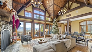 A spacious living room with a large fireplace, a Christmas tree, and a stone fireplace surround. - Renowned Architect! VIEWS/Theatre/Game/HotTub/FirePit/Harry Potter (Gatlinburg)