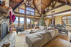 A spacious living room with a large fireplace, a Christmas tree, and a stone fireplace surround.