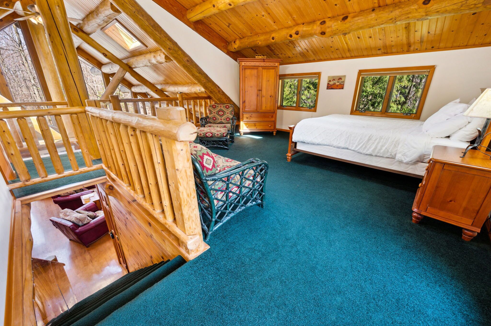 L’intérieur d’un chalet en bois, avec un lit, une armoire en bois, une chaise et un escalier.