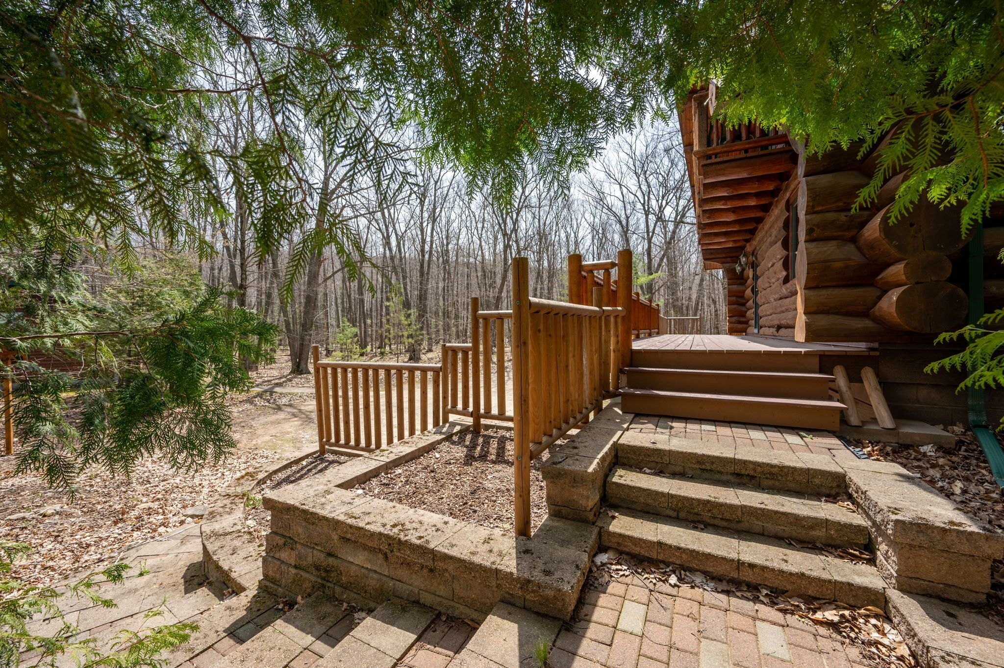 A wooden staircase leading up to a log cabin in a forested area.