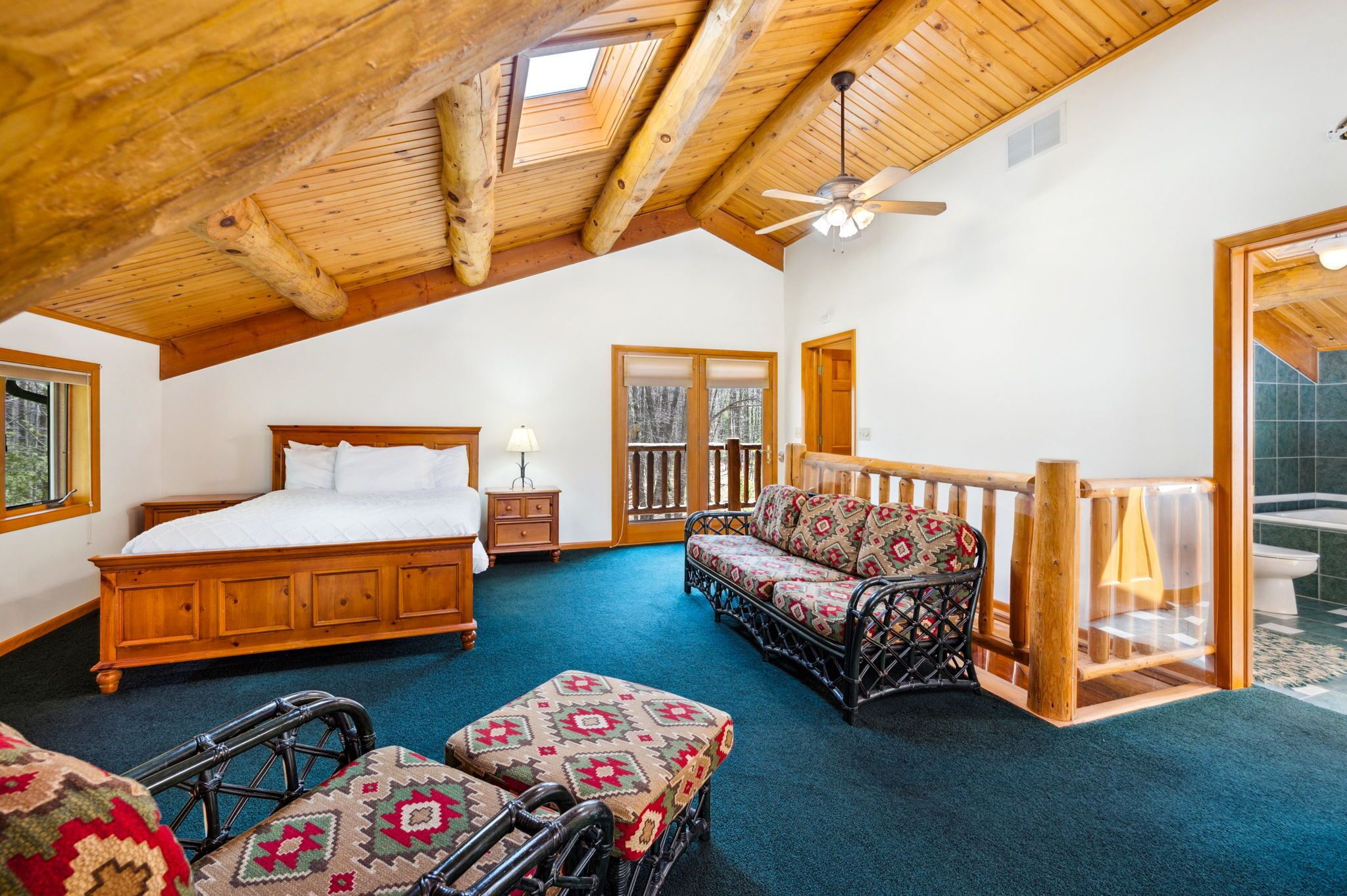 Une chambre spacieuse avec un grand lit, un canapé, un fauteuil roulant et un balcon.